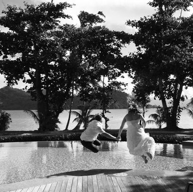 Bride and groom jumping in a pool