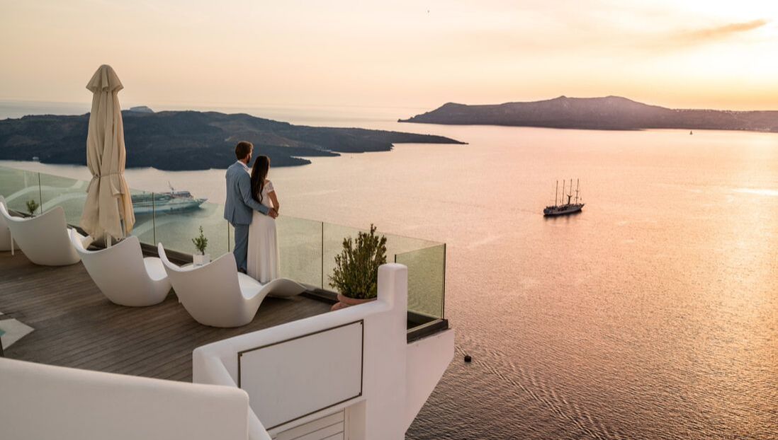 Bride and Groom on resort balcony overlooking ocean with sunset